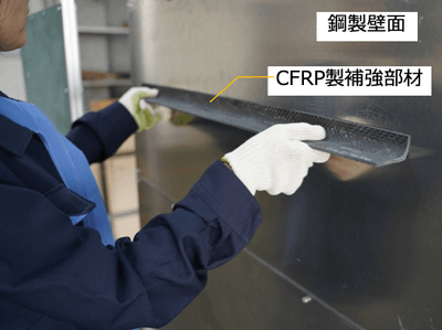 補強部材を壁面に接着している様子*（写真の試験体は本公開実験と異なります）